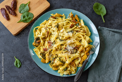 Pasta with chicken, spinach and dried tomatoes in turmeric sauce