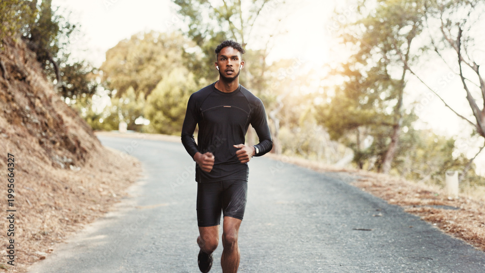 Obraz premium Man, running and earphones on mountain road for fitness, cardio development and training with podcast. Male person, runner and audio tech in nature for healthy body, outdoor challenge and music