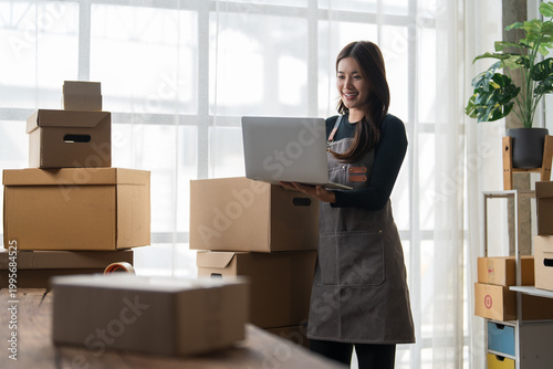 Young woman managing online business orders on laptop