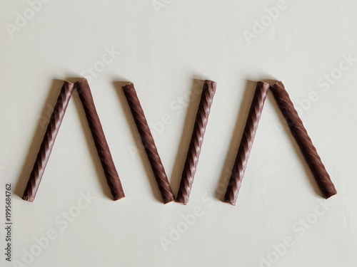 Chocolate cream rolls with mint cream on light background. Chocolate sticks, sweet dessert, candies. Top view.