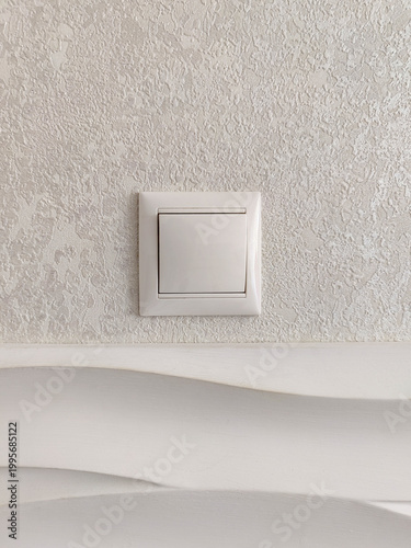 Modern light switch on textured wall. Close-up. Copy space