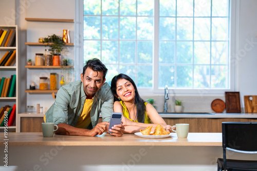 Canvas Print Happy Indian couple surfing internet and checking photos on mobile phone in mode