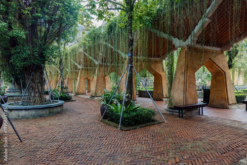 Slika na platnu A scenic view of a brick pathway lined with trees and vine-covered archways at Ba Na Hills in Da Nang, Vietnam