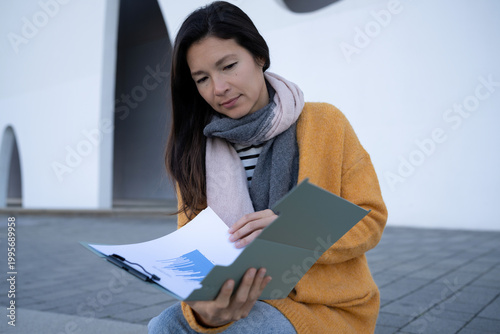 Manager reading a financial report and chart outdoors