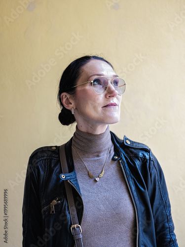 Portrait of elegant woman with glasses looking away against neutral background
