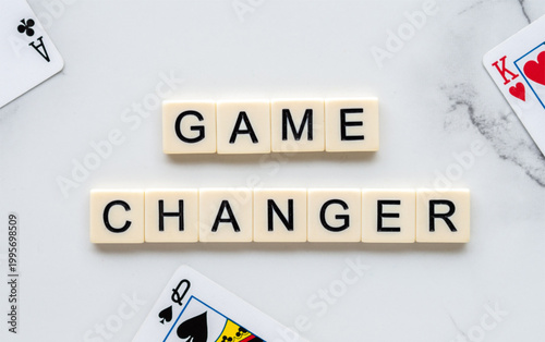 Scrabble tiles spelling 'game changer' on marble surface with playing cards