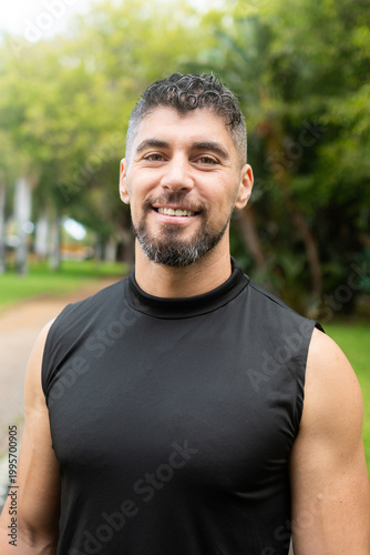 Confident male personal trainer smiling at camera outdoors in park