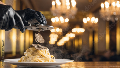 Black truffle shavings over steaming pasta in elegant restaurant with chandeliers