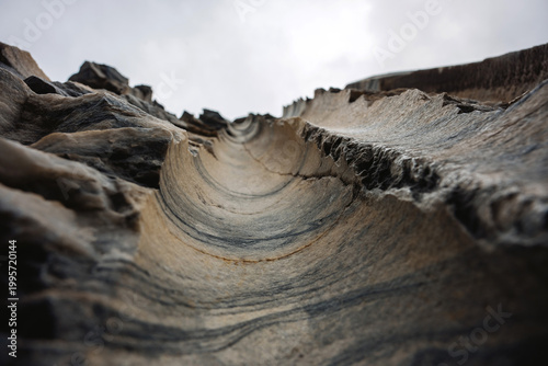 Looking up at Layered Rock Formations in a Natural Setting With Cloudy Sky in the Background During Daylight Hours
