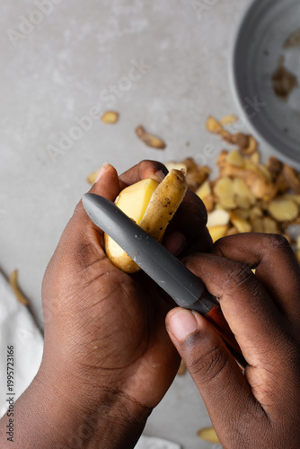 Quadro su tela Overhead view of irish potatoes being peeled over a grey countertop, top view of