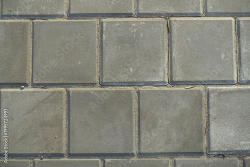 Texture of square brick-like gray concrete pavement with stack bond layout