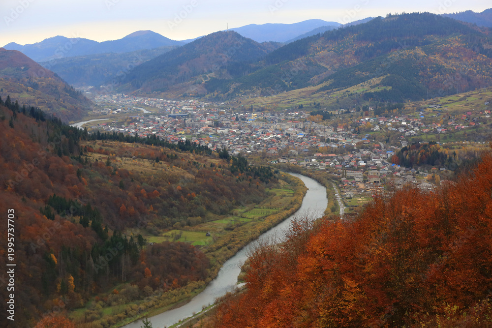 Fototapeta premium Scenic mountain valley town with a winding river and autumn foliage