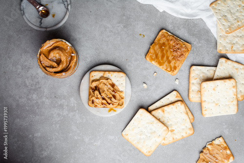 Foto Overhead view of a cracker topped with peanut butter and honey drizzle on grey c