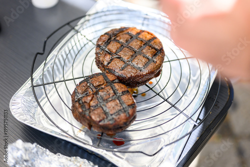 Two ribeye steaks with perfect cross-hatched sear marks rest on a wire rack in a foil tray, expertly cooked for final judging at a professional Steak Cookoff Association (SCA) BBQ competition.