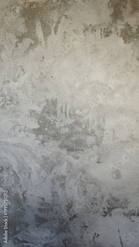 A textured concrete wall with a rough surface. The wall features various shades of gray and subtle patterns, creating an industrial aesthetic.