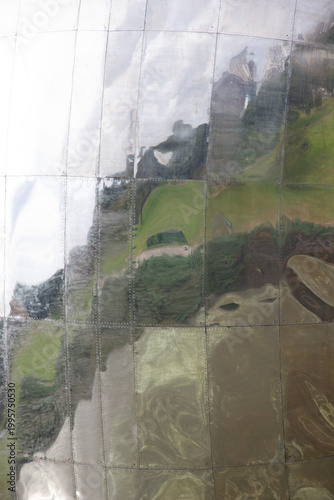 abstract, close-up shot of highly reflective surface of Floralis Genérica in Buenos Aires. grid-like assembly of stainless steel panels, held together by rivets, which mirror distorted landscape