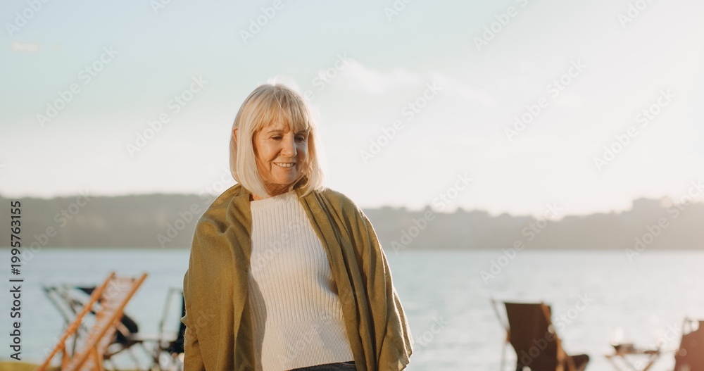 Fototapeta premium Senior woman smiling by lake enjoying leisure time