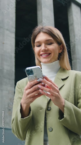 Successful young business woman uses smartphone in business district. Caucasian female employee entrepreneur uses a smartphone on urban background. Slw motion