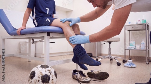 A medical professional examines the dirty and injured leg of a young soccer player in a clinic, sports injury, professional treatment, pediatric care.