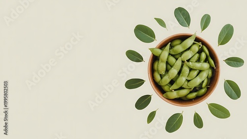 A wooden bowl filled with steamed edamame and fresh green leaves arranged to create a natural composition