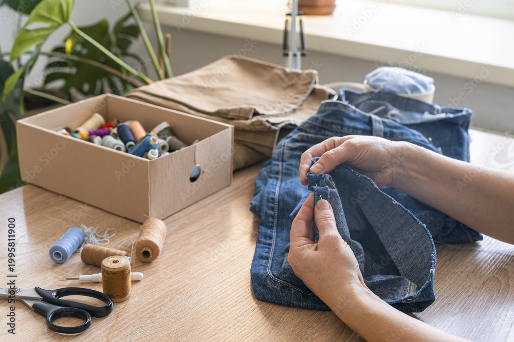 Ταπετσαρία Woman's hands sewing and repairing old denim jeans