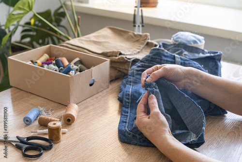 Bilde på lerret Woman's hands sewing and repairing old denim jeans