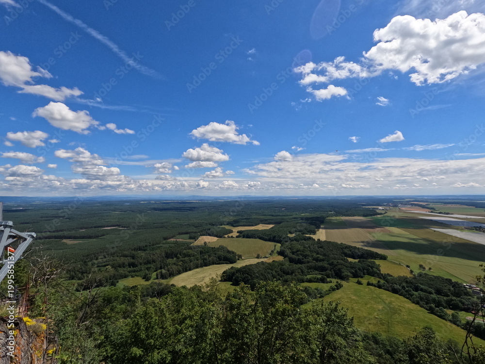 Fototapeta premium Aerial panoramic view of vast agricultural fields and lush green forests with cloud shadows under a beautiful summer sky, rural landscape.