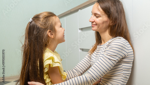 Schilderij op canvas daughter kisses and hugs her mother in the kitchen