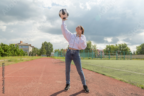 Woman throws a ball up at sport field