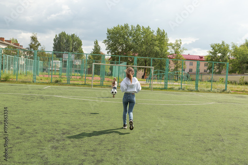 Woman playing soccer ball with her daughter at sport field