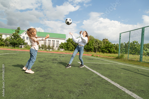 Woman playing soccer ball with her daughter at sport field