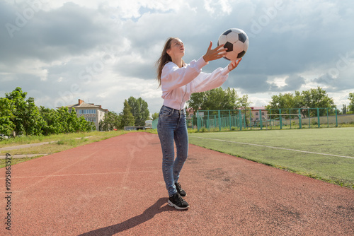 Woman throws a ball up at sport field