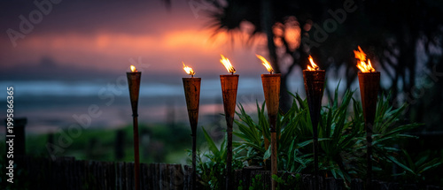 Glowing Tiki Torches in Tropical Coastal Landscape at Sunset, Warm Evening Atmosphere