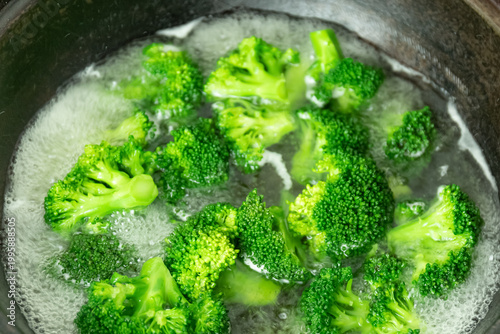 Green vegetables, such as broccoli, are boiling in boiling water in the pot.