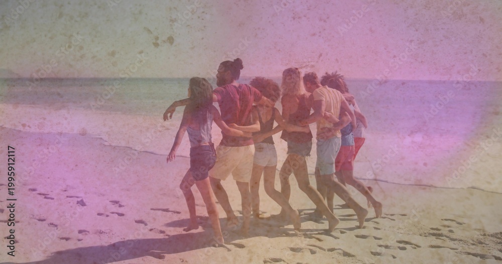 Fototapeta premium Walking seven friends linking arms and strolling along sandy shoreline with footprints, in shorts