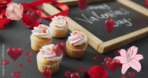 Displaying group of four frosted vanilla cupcakes on dark tabletop, with chalkboard and ribbon
