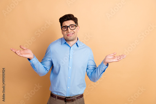 Fotografie Confused young man shrugging with uncertain expression in blue shirt and glasses