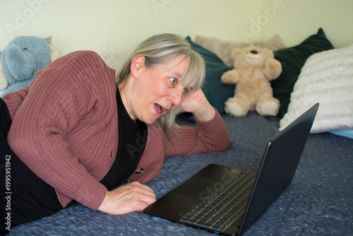 Mature woman surprised during video call looking at laptop