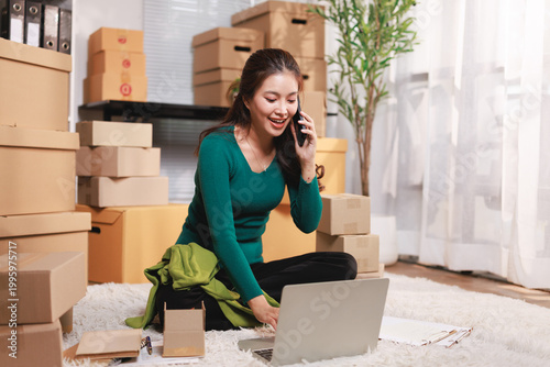 Fotografia Asian woman runs an e-commerce startup from home, talking with customers on her