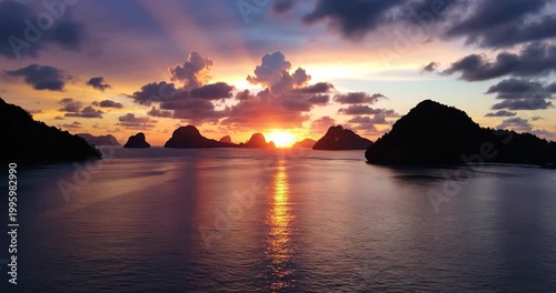 Tropical sunset over limestone islands in the ocean at dusk