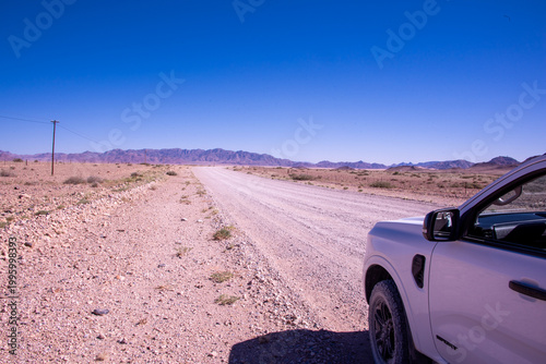 A solitary Acacia tree standing against the vast landscape of Namibia, its flat canopy silhouetted under the open sky of the African savanna.