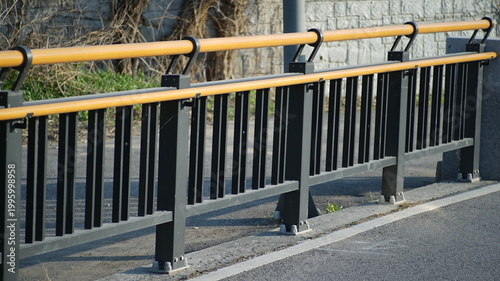 Fotografija Modern outdoor safety railing with a yellow handrail and black metal pickets on