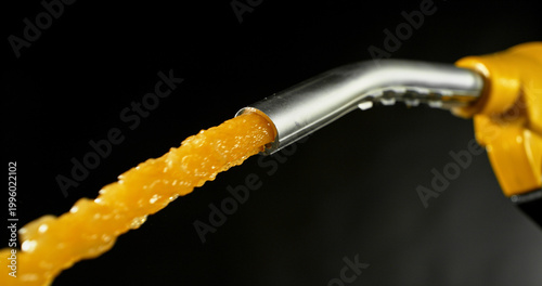 Schilderij op canvas Gasoline jet spraying from fuel nozzle on dark background, no hand visible