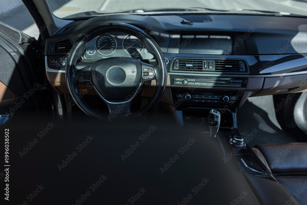 Obraz premium The interior of a premium car features a leather interior with a dashboard and a multi-function steering wheel. Taxi driver. Auto