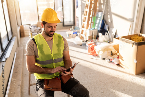 Canvastavla Construction worker uses a tablet while sitting in a work area during daylight h