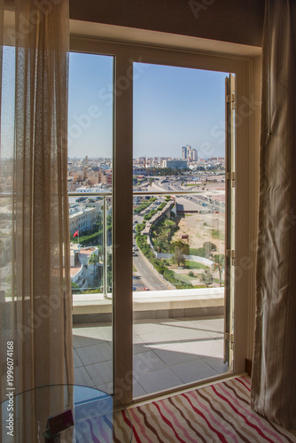 A view of Tripoli, Libya, through an open door in a high rise building, showing the highway, commonly known as the Corniche or Al-Shatt Road, visible in the image.