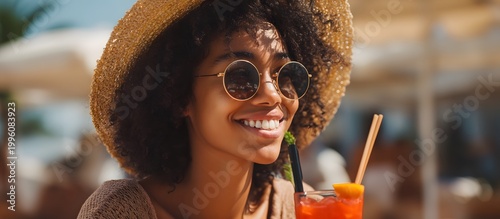Smiling woman wearing a hat and sunglasses enjoying a cocktail at the beach bar