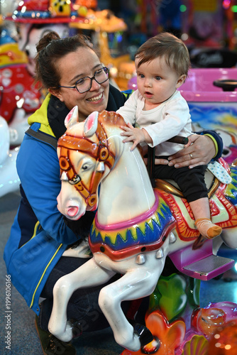 child on a horse at a nighttime fair accompanied by his mother