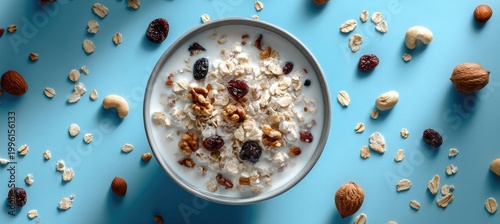A bowl of granola with milk, nuts, and dried fruit on a blue background