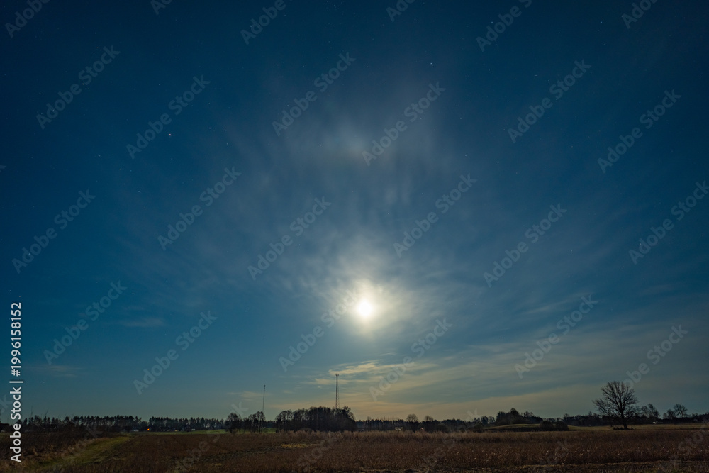 Fototapeta premium Moon halo over a quiet rural meadow at night